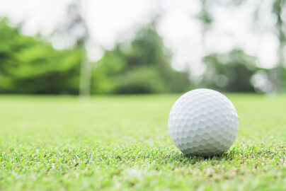 golf ball green with blurred pin flagstick green tree background