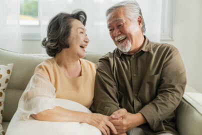 old senior asian retired age marry couple wellness lifesstyle together homeold people laugh smile together with love bonding sofa living room home interior background