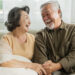 old senior asian retired age marry couple wellness lifesstyle together homeold people laugh smile together with love bonding sofa living room home interior background